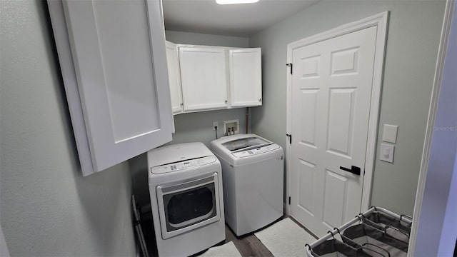 washroom with cabinets, wood-type flooring, and washing machine and clothes dryer