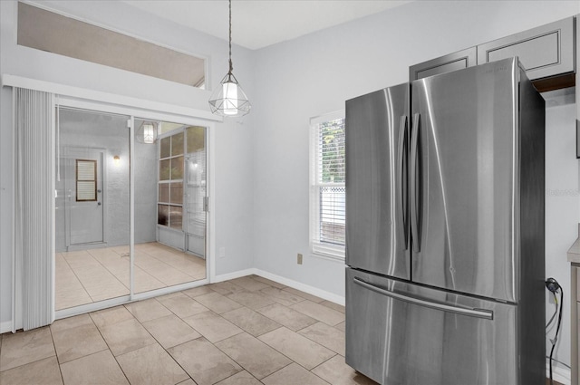 kitchen featuring light tile patterned flooring, freestanding refrigerator, baseboards, and decorative light fixtures