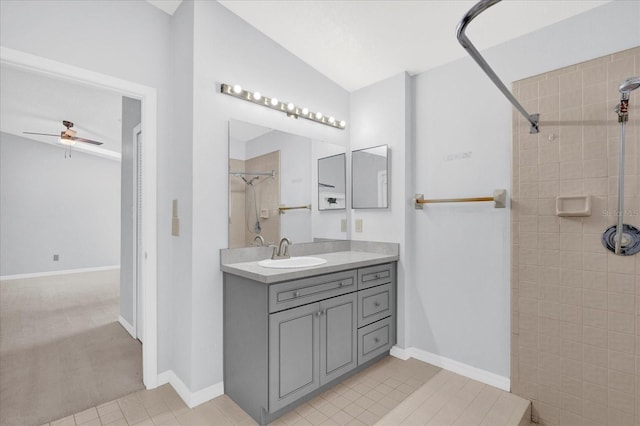 bathroom with baseboards, ceiling fan, vanity, and a tile shower