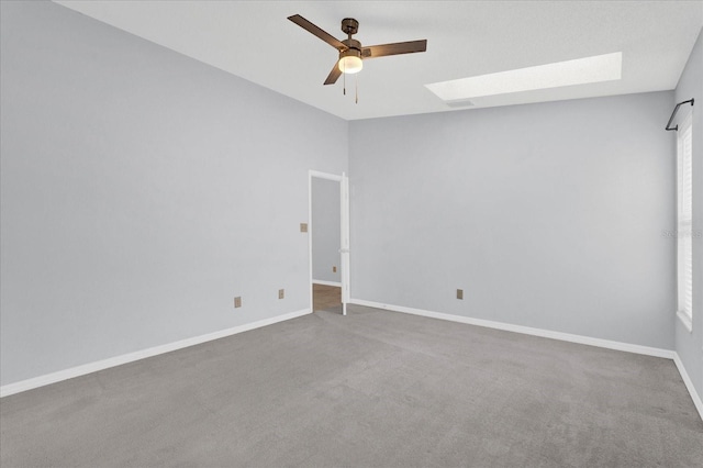 unfurnished room featuring visible vents, a ceiling fan, carpet, a skylight, and baseboards