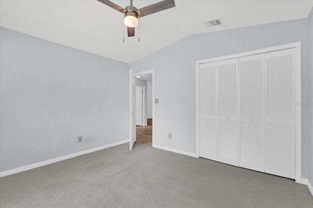 unfurnished bedroom with visible vents, a closet, carpet floors, baseboards, and vaulted ceiling