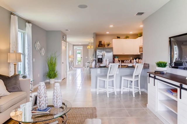 living room with light tile patterned flooring and an inviting chandelier