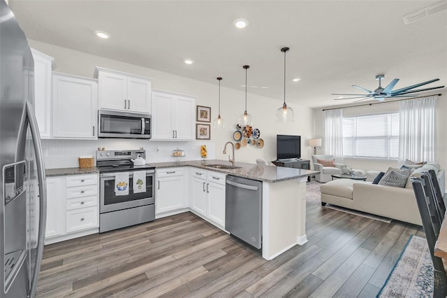 kitchen featuring pendant lighting, stone counters, white cabinetry, stainless steel appliances, and kitchen peninsula