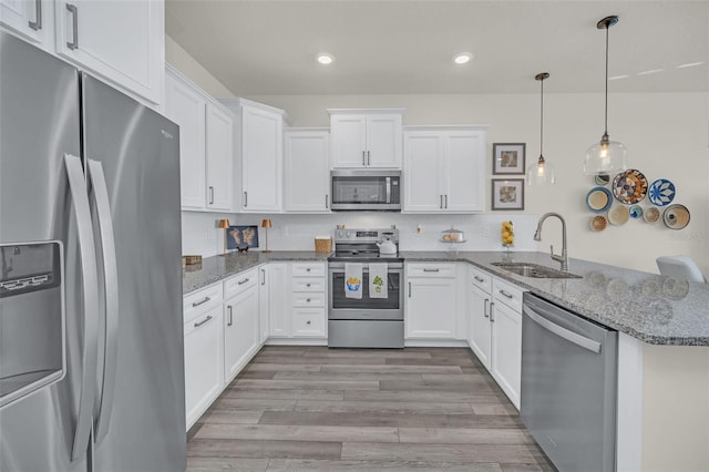 kitchen with white cabinetry, appliances with stainless steel finishes, sink, and kitchen peninsula