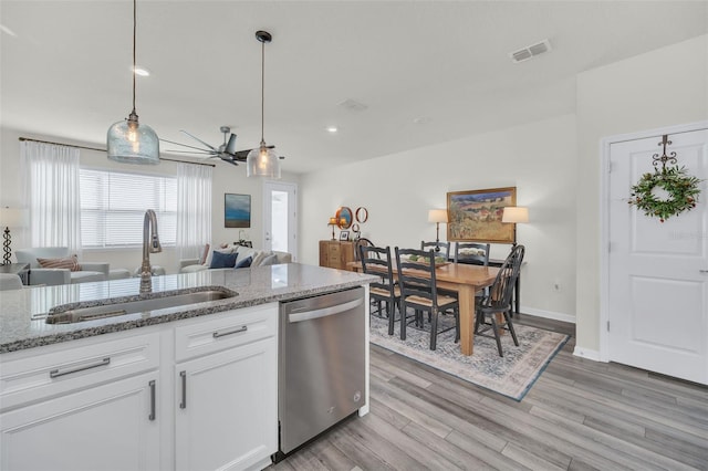 kitchen featuring sink, white cabinetry, light stone counters, hanging light fixtures, and stainless steel dishwasher