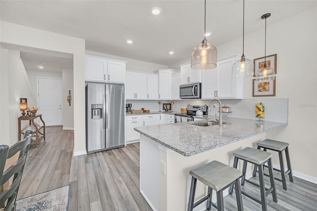 kitchen featuring sink, a breakfast bar area, white cabinetry, pendant lighting, and stainless steel appliances