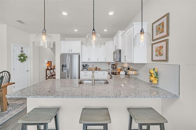 kitchen featuring stainless steel appliances, white cabinetry, and a kitchen breakfast bar