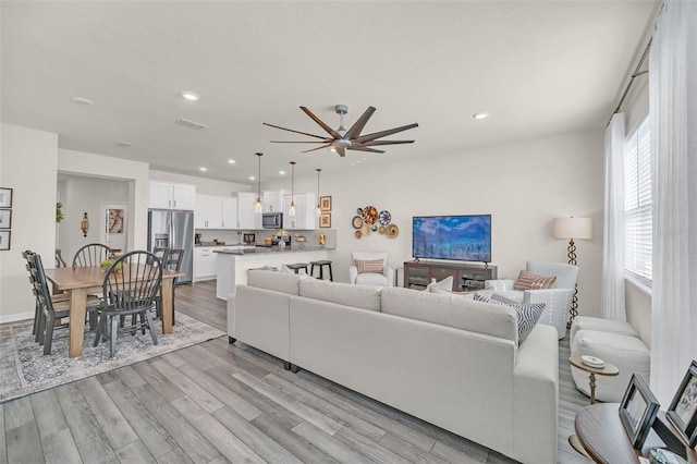 living room with ceiling fan, light hardwood / wood-style floors, and a healthy amount of sunlight