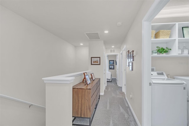 corridor with washer and clothes dryer and light colored carpet