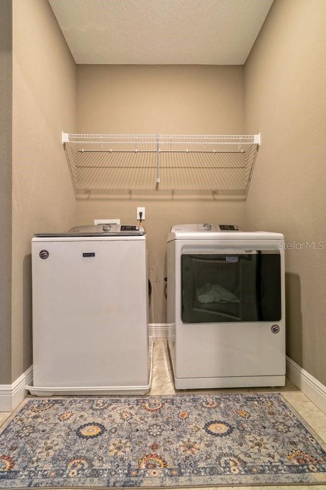 clothes washing area with tile patterned floors and independent washer and dryer