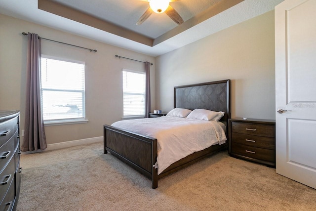 carpeted bedroom with a tray ceiling and ceiling fan