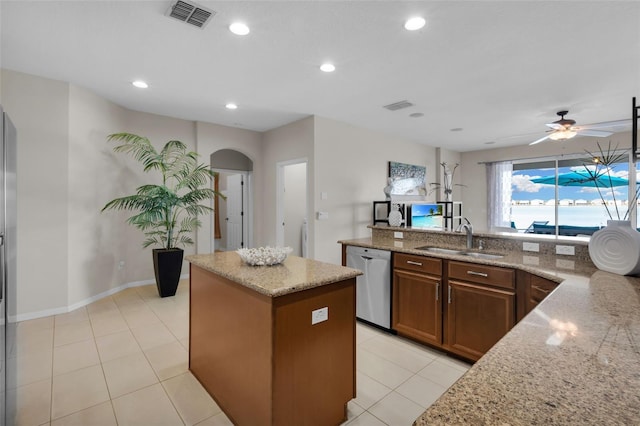 kitchen featuring sink, a kitchen island, light stone countertops, light tile patterned flooring, and stainless steel dishwasher