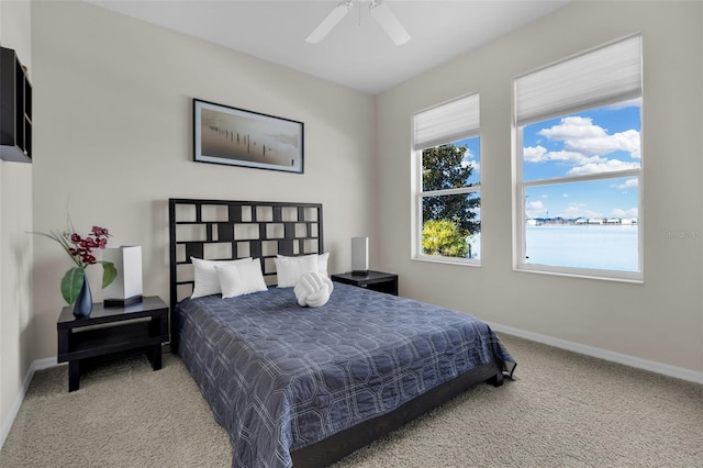 carpeted bedroom with a water view and ceiling fan