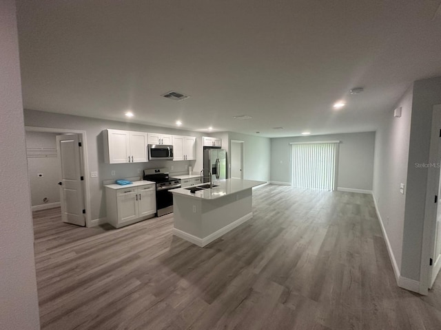 kitchen featuring sink, white cabinetry, light hardwood / wood-style flooring, appliances with stainless steel finishes, and an island with sink