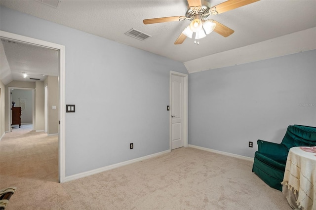 unfurnished room featuring lofted ceiling, visible vents, light carpet, and a textured ceiling