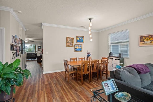 dining space with ornamental molding, a textured ceiling, baseboards, and wood finished floors