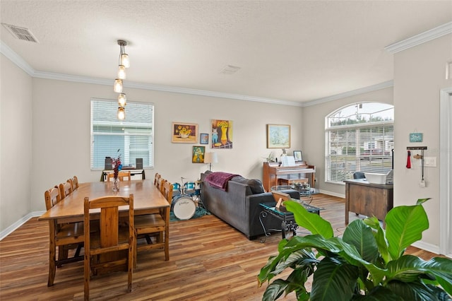 dining room with visible vents, crown molding, baseboards, and wood finished floors