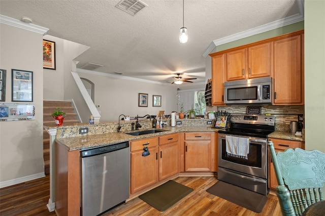 kitchen featuring visible vents, appliances with stainless steel finishes, a sink, wood finished floors, and a peninsula