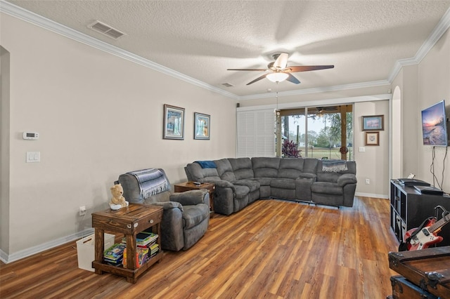 living area featuring ceiling fan, ornamental molding, wood finished floors, and visible vents