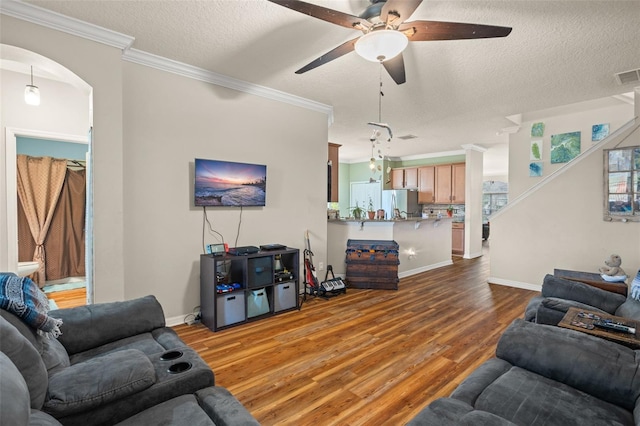 living area with a textured ceiling, ornamental molding, wood finished floors, and a ceiling fan