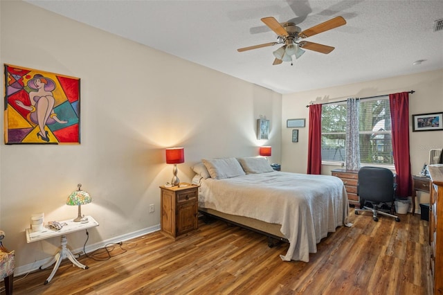 bedroom featuring a ceiling fan, a textured ceiling, baseboards, and wood finished floors