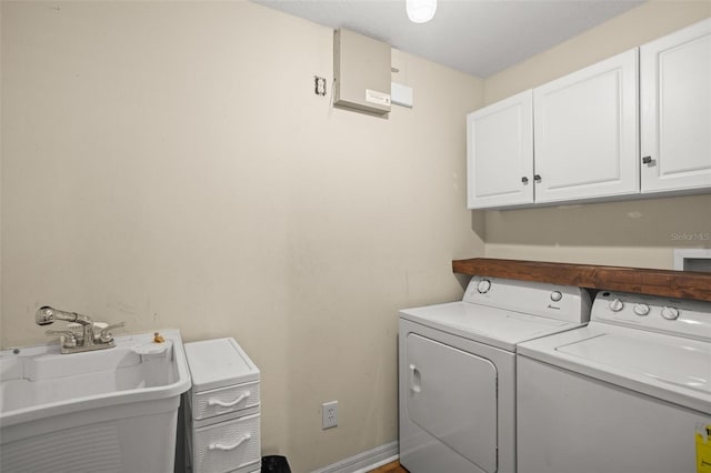 laundry room featuring a sink, washing machine and clothes dryer, cabinet space, and baseboards