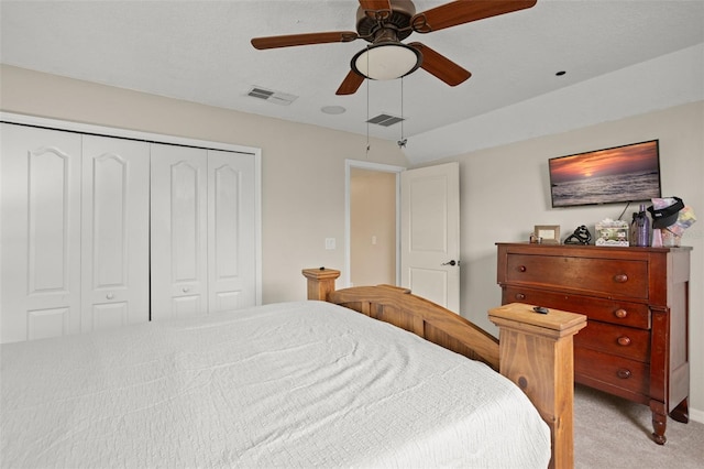 bedroom with light carpet, ceiling fan, visible vents, and a closet