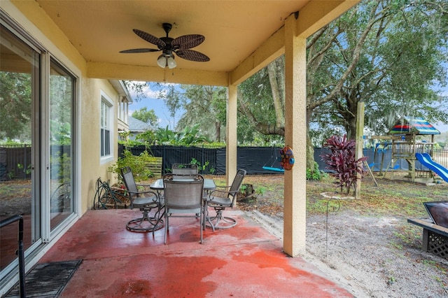 view of patio / terrace with outdoor dining space, a playground, a fenced backyard, and a ceiling fan