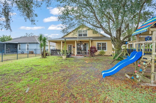 exterior space featuring fence, a front lawn, a playground, and stucco siding