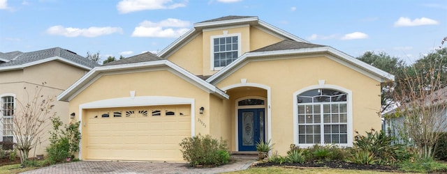 traditional home with decorative driveway, an attached garage, and stucco siding