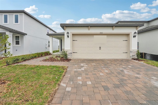 view of front of property featuring decorative driveway, stone siding, an attached garage, and stucco siding