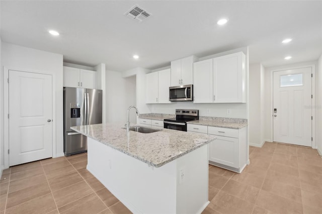 kitchen with visible vents, a kitchen island with sink, a sink, appliances with stainless steel finishes, and white cabinets