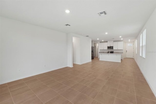 unfurnished living room featuring recessed lighting, visible vents, and baseboards