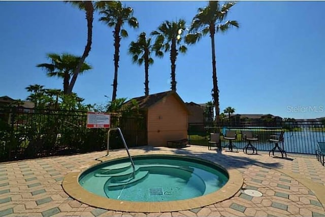 view of pool with a patio, a water view, and a community hot tub