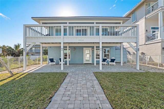 rear view of house with a wooden deck, a yard, and a patio area