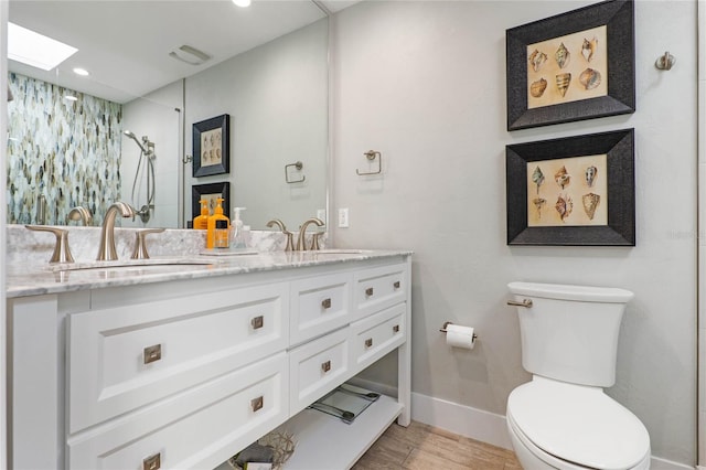 bathroom with vanity, toilet, a skylight, and a tile shower