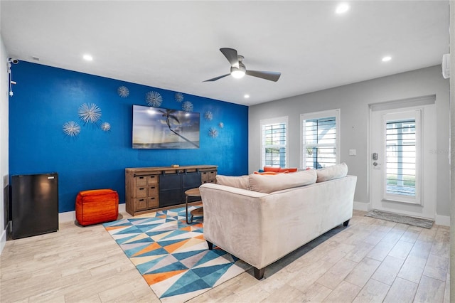 living area with wood finished floors, a ceiling fan, an accent wall, and recessed lighting