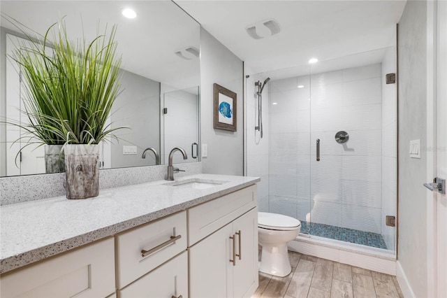 full bathroom featuring toilet, a shower stall, wood finished floors, and vanity