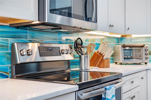 kitchen with light countertops, appliances with stainless steel finishes, backsplash, and a toaster