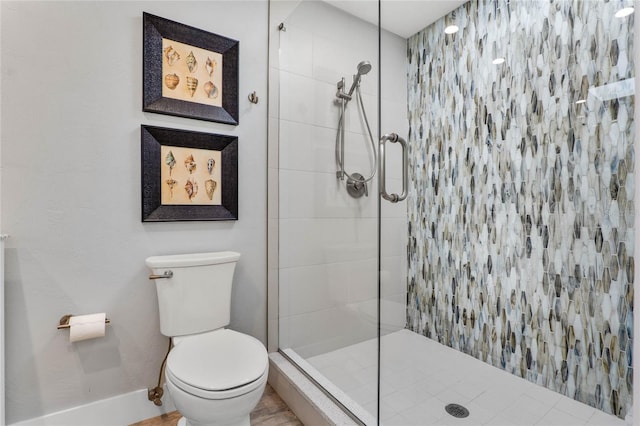 bathroom with baseboards, a tile shower, and toilet