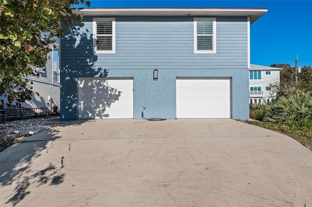 exterior space featuring an attached garage, stucco siding, and concrete driveway