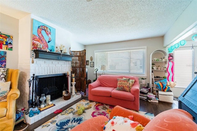 living room with hardwood / wood-style floors, built in shelves, a fireplace, and a textured ceiling