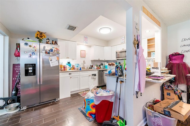 kitchen with white cabinetry, stainless steel appliances, sink, and tasteful backsplash