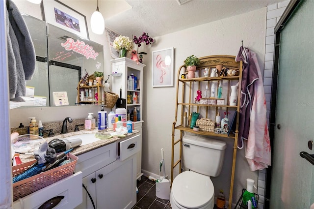 bathroom featuring a shower with shower door, tile patterned flooring, vanity, toilet, and a textured ceiling