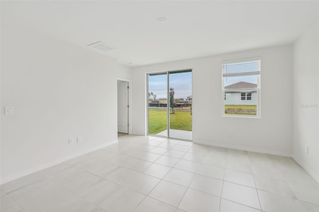 spare room featuring light tile patterned floors, visible vents, and baseboards