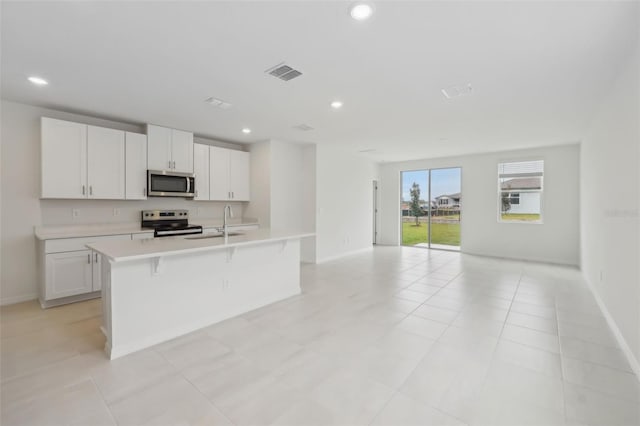 kitchen with visible vents, a center island with sink, recessed lighting, appliances with stainless steel finishes, and light countertops