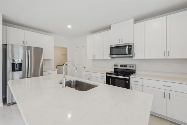 kitchen with a sink, stainless steel appliances, an island with sink, and white cabinets