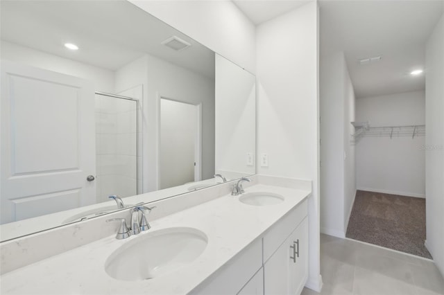 bathroom featuring double vanity, a walk in closet, and a sink