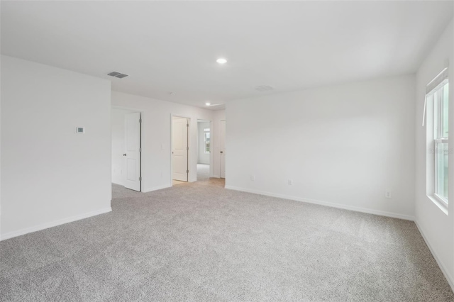 empty room featuring recessed lighting, light colored carpet, visible vents, and baseboards