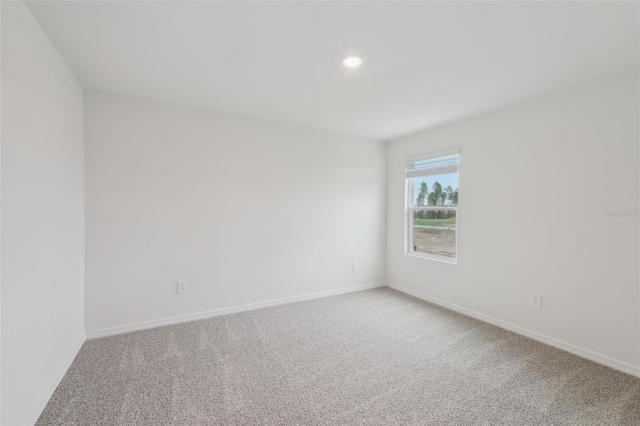 spare room featuring recessed lighting, light colored carpet, and baseboards